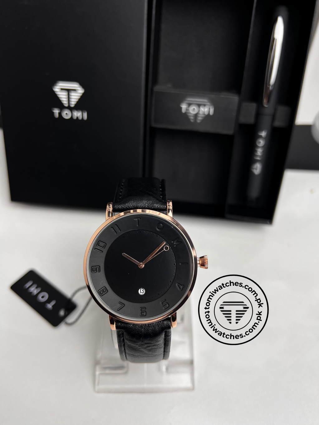 Black dial TOMI T-085 watch with rose gold case displayed on a presentation stand
