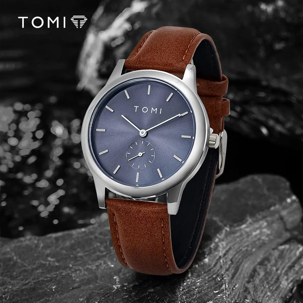TOMI T-088 Business Quartz Unisex Watch – Silver-cased model with a blue dial and brown leather strap, angled on a dark textured background.