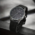 TOMI T-071 Men's Watch Date Quartz - Black dial watch with black leather strap sitting on a dark ledge.
